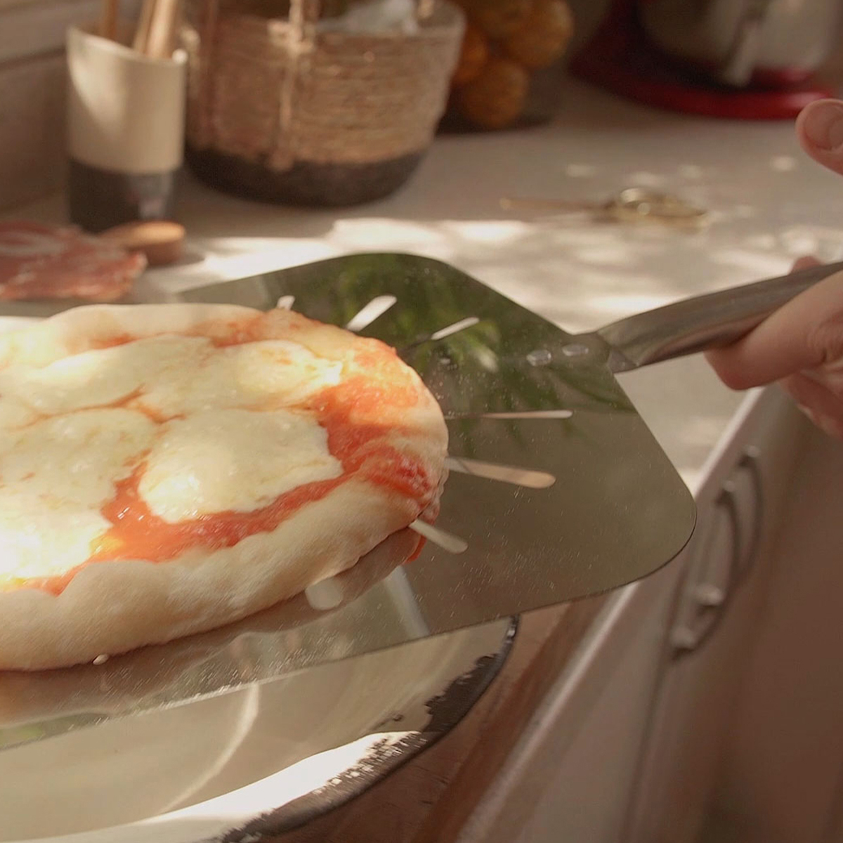 Pala pizzera de carga sosteniendo una pizza de muzzarella recién horneada