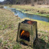 Biocalentador encastrable encendido con leña, al aire libre junto a un arroyo