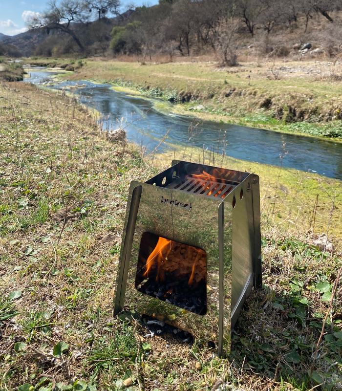 Biocalentador encastrable encendido con leña, al aire libre junto a un arroyo