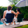 Dos personas sentadas en sillones playeros bajos junto a una pileta