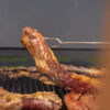 6113-CONTEXTO.jpg Tenedor parrillero sosteniendo un corte de carne sobre la parrilla